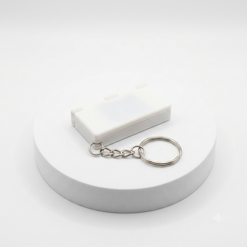A small white rectangular plastic case with a silver metal key ring and short chain, displayed on a round white pedestal against a clean white background.