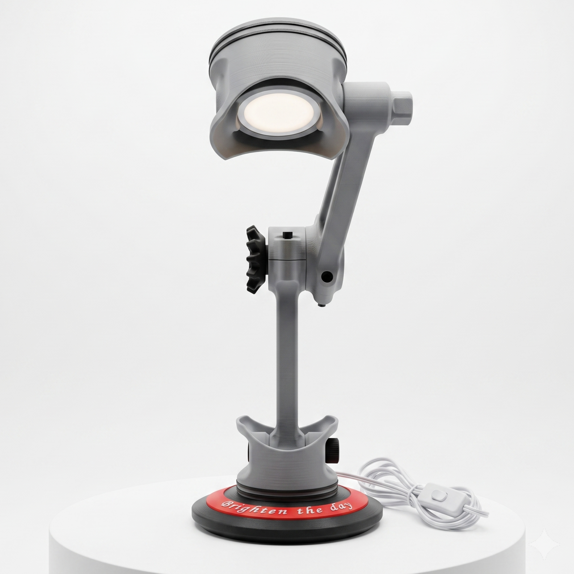 A gray adjustable desk magnifier lamp with a circular head, mounted on a stand with a red circular base, shown on a white cylindrical pedestal against a light gray background.